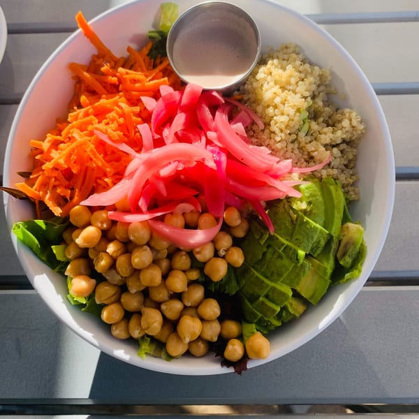 A colorful bowl from The Cabana Bar & Grill with chickpeas, avocado, quinoa, pickled onions, and shredded carrots.