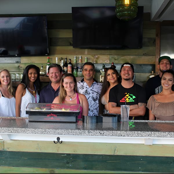 Nine smiling staff members of The Cabana Bar & Grill standing behind a bar with bottles.